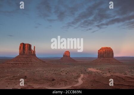 Die Sonne geht auf den Fäusten und Merrick Butte im Monument Valley unter, während der Mond hinter ihnen aufgeht, Arizona/Utah, USA Stockfoto