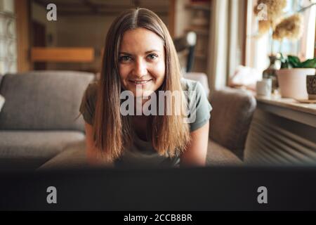 Porträt einer attraktiven jungen Frau mit langen braunen Haaren lächelnd Zu Hause Stockfoto