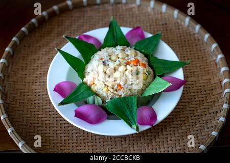 Vietnamesische gesunde Lebensmittel zum Mittag-oder Abendessen, gebratener Reis mit Gemüse, Lotussamen, Bohne in einem Lotusblatt auf dem Hintergrund der Lotusblume eingewickelt Stockfoto