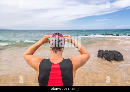 Triathlon-Schwimmer geht schwimmen bereit, Blick auf den Ozean Horizont. Mann Triathlet Schwimmer Putting Goggles für den Wettbewerb. Profisportler Stockfoto