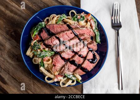 Cremiges Steak fettuccini mit Spinat und getrockneten Tomaten Stockfoto