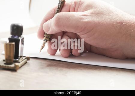 Hand eines Mannes, der einen Brief oder eine Notiz mit einem grünen Stift und schwarzer Tinte schreibt. Stockfoto