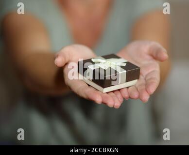 Geschenk in dekorativer Box mit Band in offenen Frauen Hände close up, geben Überraschung präsent Stockfoto