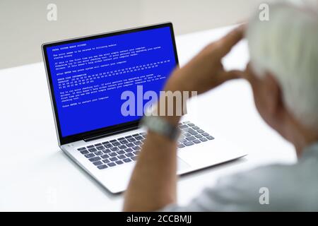 Senior mit BSOD Death Screen auf einem gehackten Laptop Stockfoto