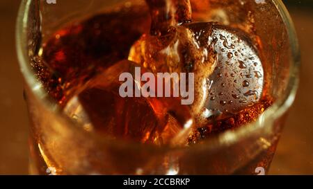 Super Makro Schuss von Gießen Cola-Getränk in Glas. Eiswürfel innen. Stockfoto