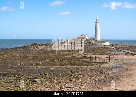 St Mary's Insel und Leuchtturm bei Ebbe mit Menschen, die den Damm in Whitley Bay, Nordostengland, Großbritannien überqueren Stockfoto