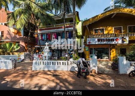 Candolim, North Goa, Indien - 23. November 2019: Straßenansicht von Goa an sonnigen Tag mit geparkten Fahrrädern in der Nähe von Touristenläden und Apotheke in Candolim, North G Stockfoto