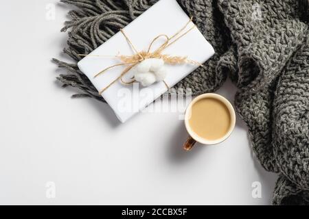 Tasse Kaffee, Geschenkbox und Strickschal auf weißem Hintergrund. Hygge Stil flach Lay Zusammensetzung, Herbst-Konzept. Gemütlicher Schreibtisch mit Blick von oben. Stockfoto