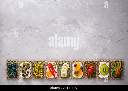 Hausgemachte Sandwiches mit Gemüse, Obst, Beeren, Chlorella, Spirulina und Käse. Heidelbeere, Traube, Mais, Pfeffer, Banane, Mandarine, Tomaten, Kiwi Stockfoto