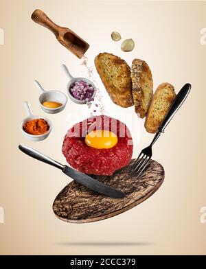 Steak Tartar mit Gewürzen und Toast fliegen. Konzept des Fliegens Lebensmitteln in geringer Schwerkraft. Bild mit sehr hoher Auflösung. Auf farbigem Hintergrund getrennt Stockfoto