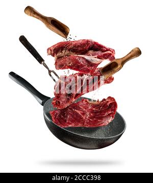 Fliegen rohe Steaks mit Zutaten zum Kochen, aus der Pfanne nehmen. Holzschalen mit Gewürzen. Konzept der Zubereitung von Speisen. Isoliert auf weißem Hintergrund. Zusätzliche Stockfoto