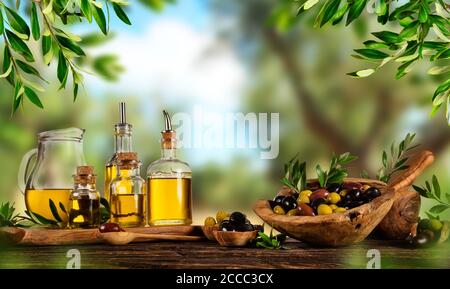 Frisch geerntete Oliven Beeren in Holz Schalen und kaltgepresstes Öl in Glasflaschen. Stillleben der Zubereitung von Speisen serviert auf alten Holzdielen. Kostenlose spac Stockfoto