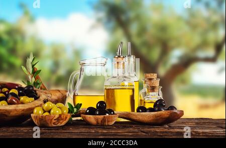 Frisch geerntete Oliven Beeren in Holz Schalen und kaltgepresstes Öl in Glasflaschen. Stillleben der Zubereitung von Speisen serviert auf alten Holzdielen. Kostenlose spac Stockfoto