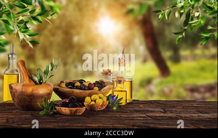 Frisch geerntete Oliven Beeren in Holz Schalen und kaltgepresstes Öl in Glasflaschen. Stillleben der Zubereitung von Speisen serviert auf alten Holzdielen. Kostenlose spac Stockfoto