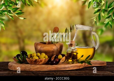 Frisch geerntete Oliven Beeren in Holz Schalen und kaltgepresstes Öl in Glasflaschen. Stillleben der Zubereitung von Speisen serviert auf alten Holzdielen. Kostenlose spac Stockfoto