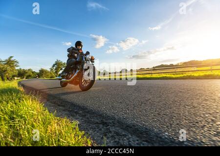 Dunkle Motorradfahrer Reiten High Power Motorrad in der Natur mit schönen Sonnenuntergang Licht. Reisen und Transport. Freiheit beim Motorradfahren Stockfoto