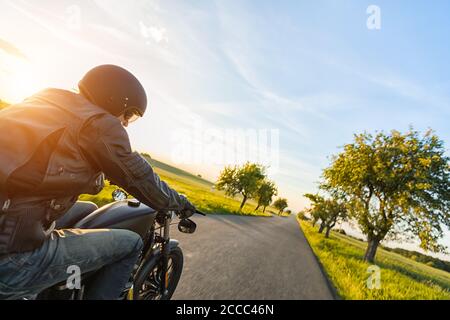 Dunkle Motorradfahrer Reiten High Power Motorrad in der Natur mit schönen Sonnenuntergang Licht. Reisen und Transport. Freiheit beim Motorradfahren Stockfoto