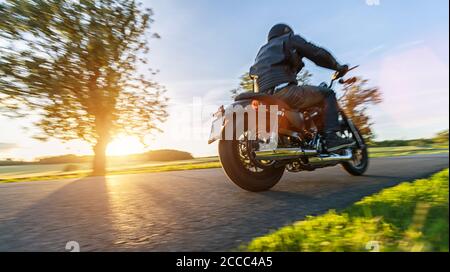 Dunkle Motorradfahrer Reiten High Power Motorrad in der Natur mit schönen Sonnenuntergang Licht. Reisen und Transport. Freiheit beim Motorradfahren Stockfoto