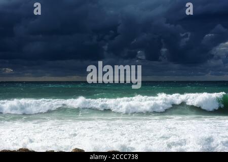 Ein heftiger Sturm im Meer. Wunderschöne blaue Sturmwolken. Eine trübe, bedrohliche Landschaft. Eine schreckliche Sturmwarnung. Wellen brechen an der felsigen Küste. Stockfoto