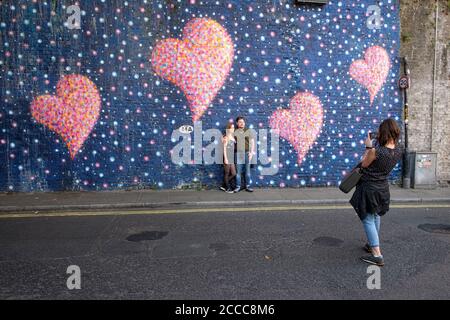 Paar posiert für ein Foto von einem Wandbild unter der Eisenbahnbrücke in der Stoney Street, in der Nähe von Borough Market, Southwark, London Stockfoto