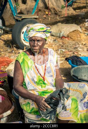 Frau auf dem Markt sitzt auf einem Plastikbehälter wartet auf Kunden in Senegal, Afrika - Foto: Iris de Reus Stockfoto