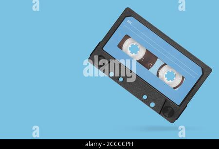 Alte Audioband-Kompaktkassette mit leerem Etikett isoliert auf blauem Hintergrund. Beschneidungspfad Stockfoto