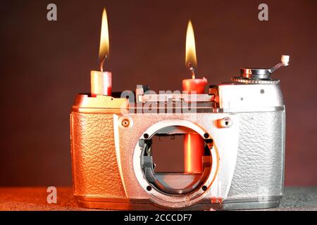Nahaufnahme einer alten kaputten Kamera mit brennenden Kerzen an Es auf einem verschwommenen Hintergrund Stockfoto