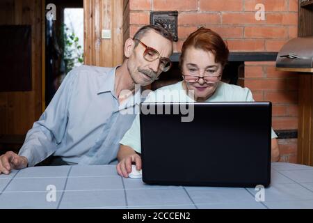 Seniorenpaar mit Laptop und modernen Technologien. Surfen im Internet Stockfoto