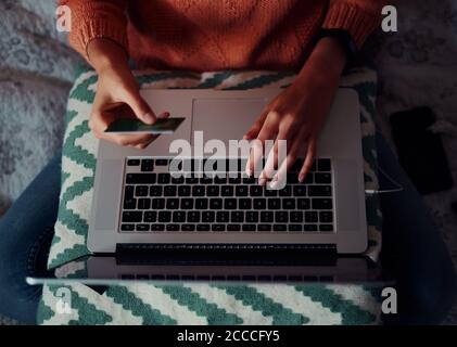 Nahaufnahme der jungen Frau, die eine Bann-Karte in der Hand hält Für die Online-Zahlung mit Laptop zu Hause Stockfoto