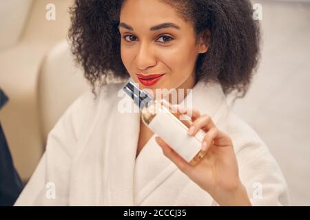 Charmante Dame mit kosmetischem Produkt in der Hand Stockfoto