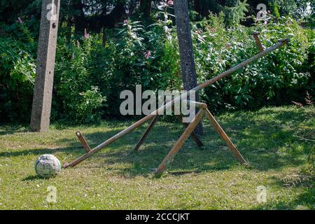 Verlassene Spielplatz an einem sonnigen Tag. Man sieht eine gebrochene Schaukel und einen Fußball ohne Luft. Stockfoto