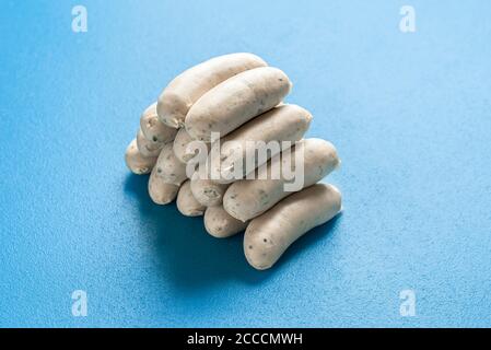 Haufen bayerischer Weißwurst isoliert auf blauem Hintergrund. Traditionelle deutsche Kalbswürste in pyramidenförmiger Form gestapelt. Hausgemachte Speisen. Stockfoto