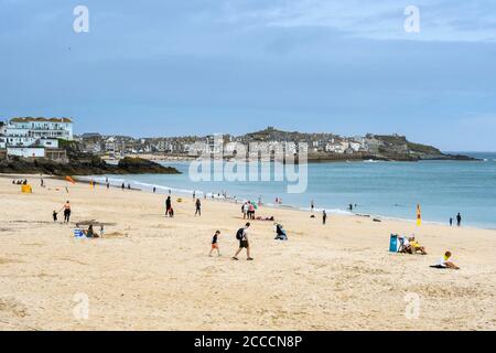 St Ives, Cornwall, Großbritannien. August 2020. Wetter in Großbritannien. Ein paar Urlauber am Strand im Badeort St. Ives in Cornwall an einem Tag von trüber Sonne und starken böigen Winden. Bild: Graham Hunt/Alamy Live News Stockfoto