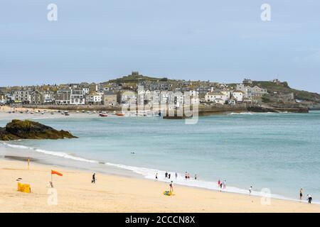 St Ives, Cornwall, Großbritannien. August 2020. Wetter in Großbritannien. Ein paar Urlauber am Strand im Badeort St. Ives in Cornwall an einem Tag von trüber Sonne und starken böigen Winden. Bild: Graham Hunt/Alamy Live News Stockfoto