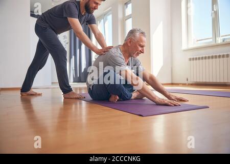 Reifer Yogi Student Training unterstützt von seinem Trainer Stockfoto