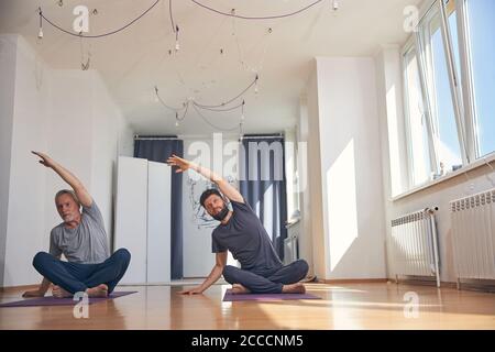 Zwei flexible kaukasische Männer üben zusammen Yoga Stockfoto