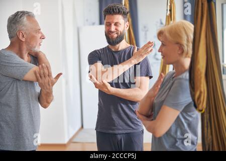 Lächelnder professioneller Trainer zeigt eine Stretching-Übung Stockfoto