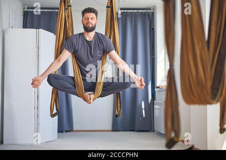 Mann meditiert in einer Yoga-Hängematte Stockfoto