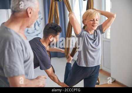 Fröhliche Frau, die eine Yoga-Übung aus der Luft durchführt Stockfoto