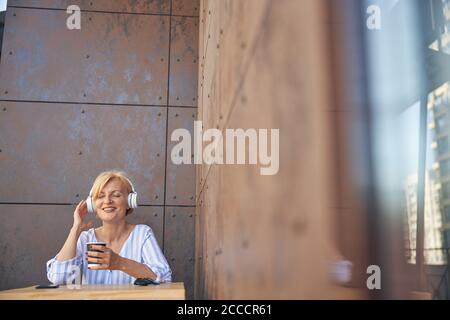 Fröhliche Dame in Kopfhörer genießen ihre Lieblings-Songs Stockfoto