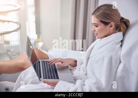 Glückliche junge Frau mit Laptop im Spa-Salon Stockfoto