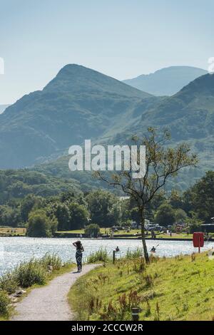 Eine junge Dame, die am beliebten Llyn Padarn Lake im Snowdonia National Park, North Wales, England, entlang geht Stockfoto