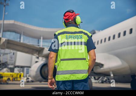 Flughafenmitarbeiter, der ein geparktes Flugzeug anschaut Stockfoto