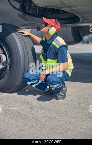 Flughafenmitarbeiter, der eine Sichtprüfung des Fahrgestells durchführt Stockfoto