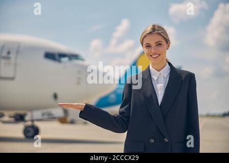 Junge Fluglinienangestellte lächelt an der Kamera Stockfoto