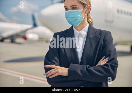 Blonde moderne Frau mit gefalteten Armen wegschauen Stockfoto