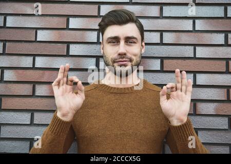 Junger erwachsener Mann über brauner Ziegelwand schreiend stolz und feiert Sieg und Erfolg sehr aufgeregt, jubelnde Emotion. Stockfoto