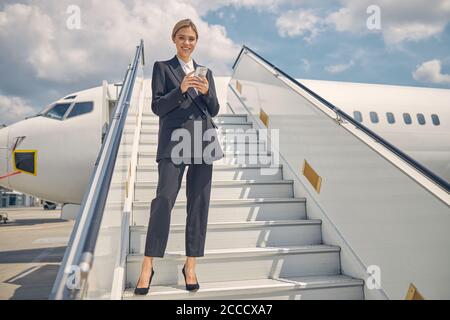 Lächelnde kaukasische Frau hält ein Mobiltelefon Stockfoto