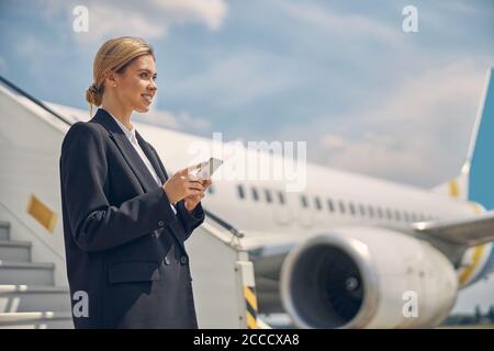 Lächelnd attraktive junge Frau hält ein Gadget Stockfoto