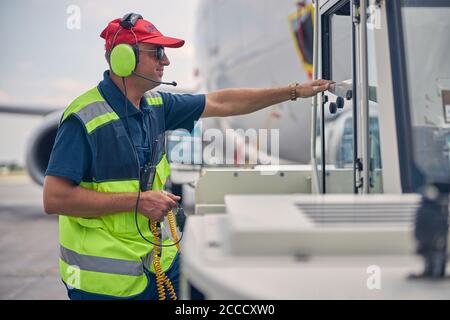 Flughafenmitarbeiter steht vor einem Rückschleppwagen Stockfoto